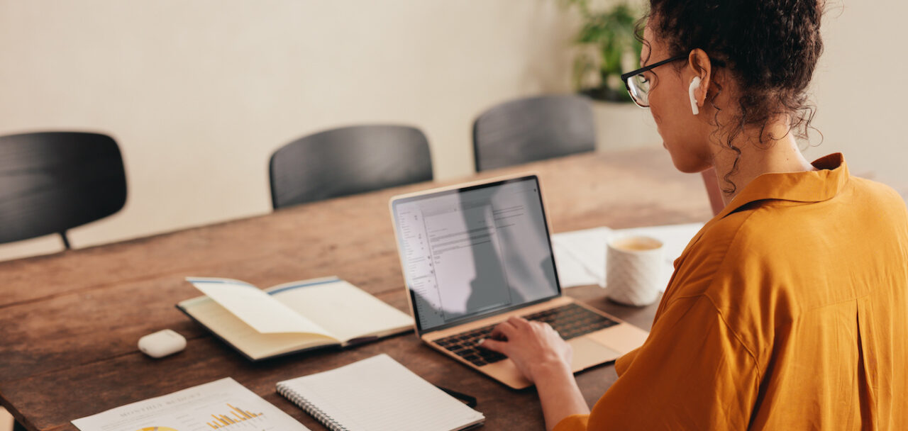 Woman working at laptop with paper