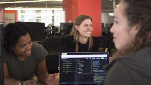 Women technologists around laptop