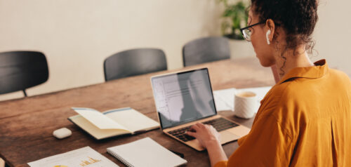 Woman working at laptop with paper